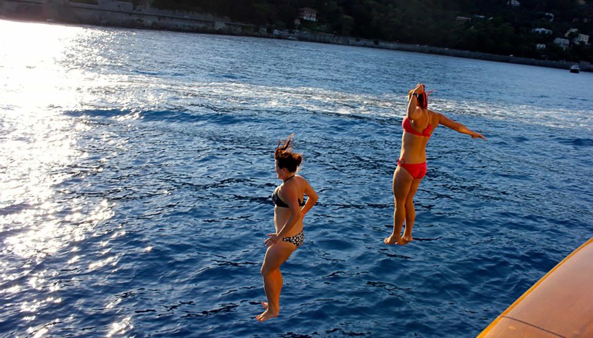 Two women jumping from their yacht into the ocean