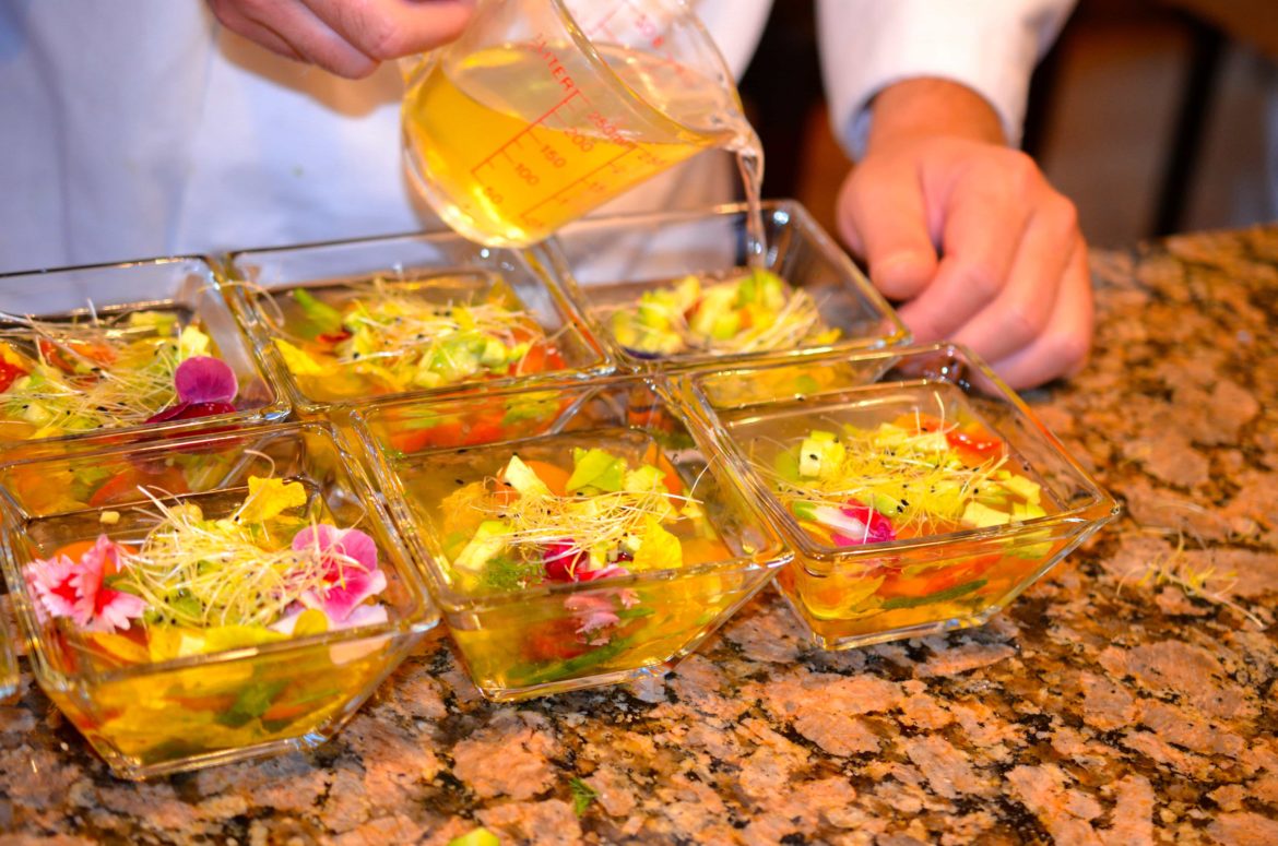 Superyacht chef serving beautifully garnished gaspacho.