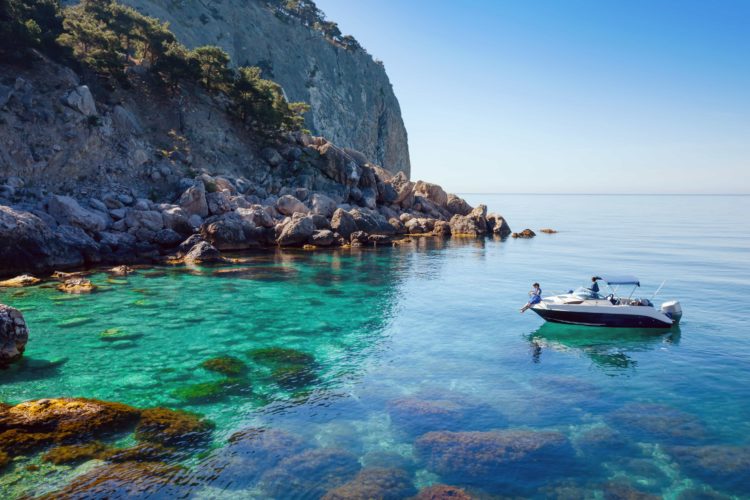 boat near cliffs of Greece on crystal blue water