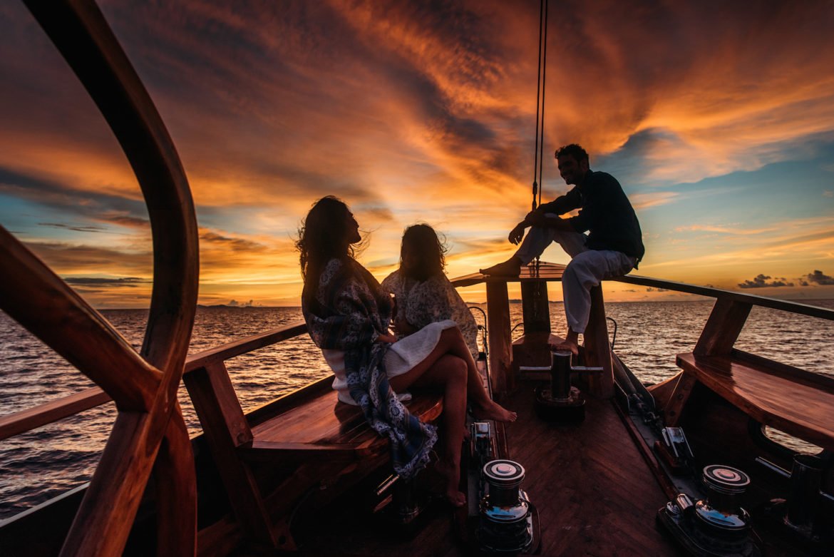 family on bow of yacht at sunset