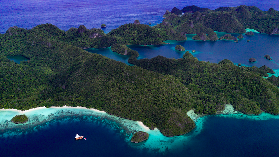 Bird's eye view of sailing yacht Sequoia sailing in the saphire waters surrounding the Indonesian Islands. 