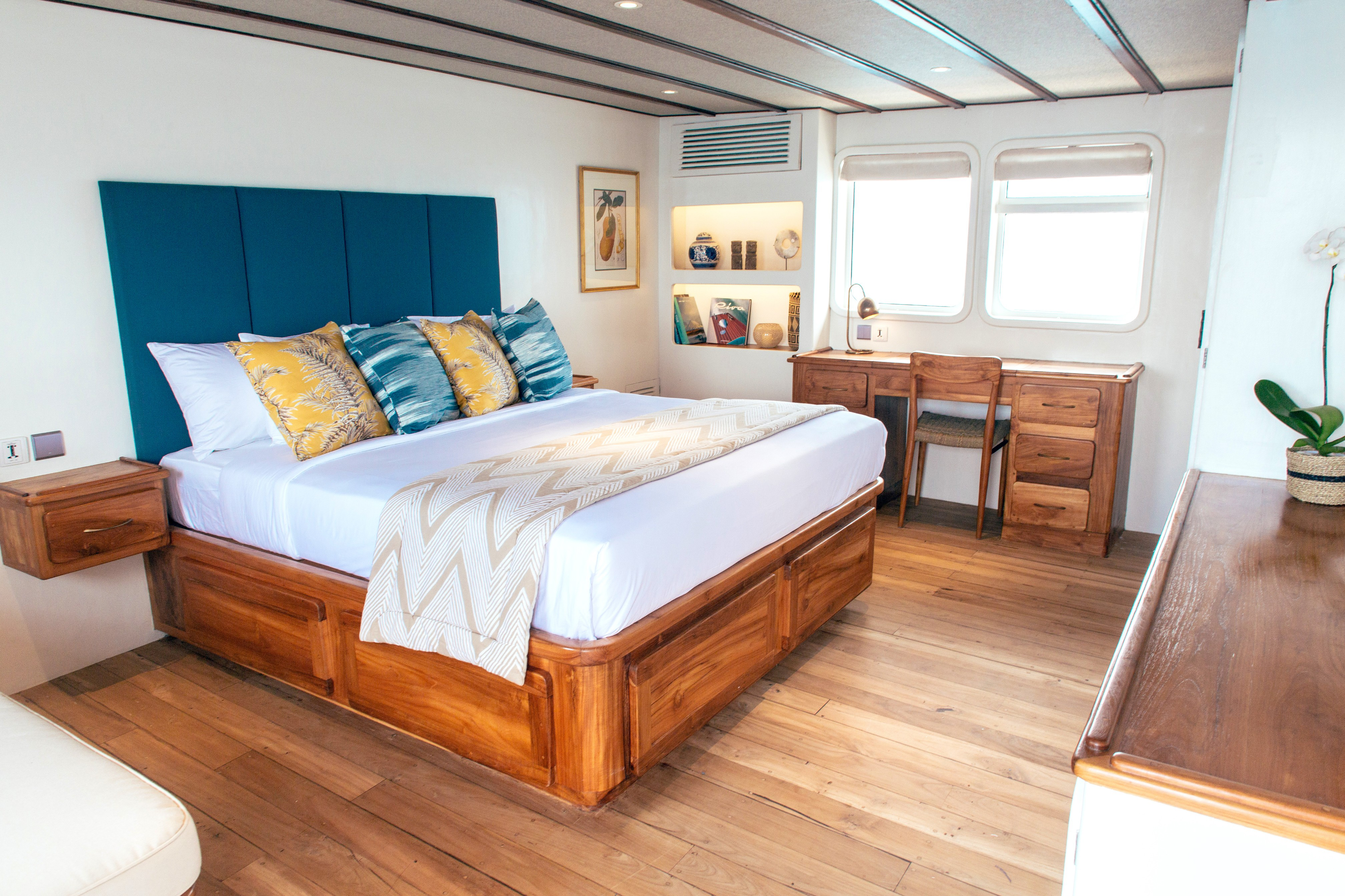 master bedroom onboard a luxury yacht in tasteful light colours and modern teak.