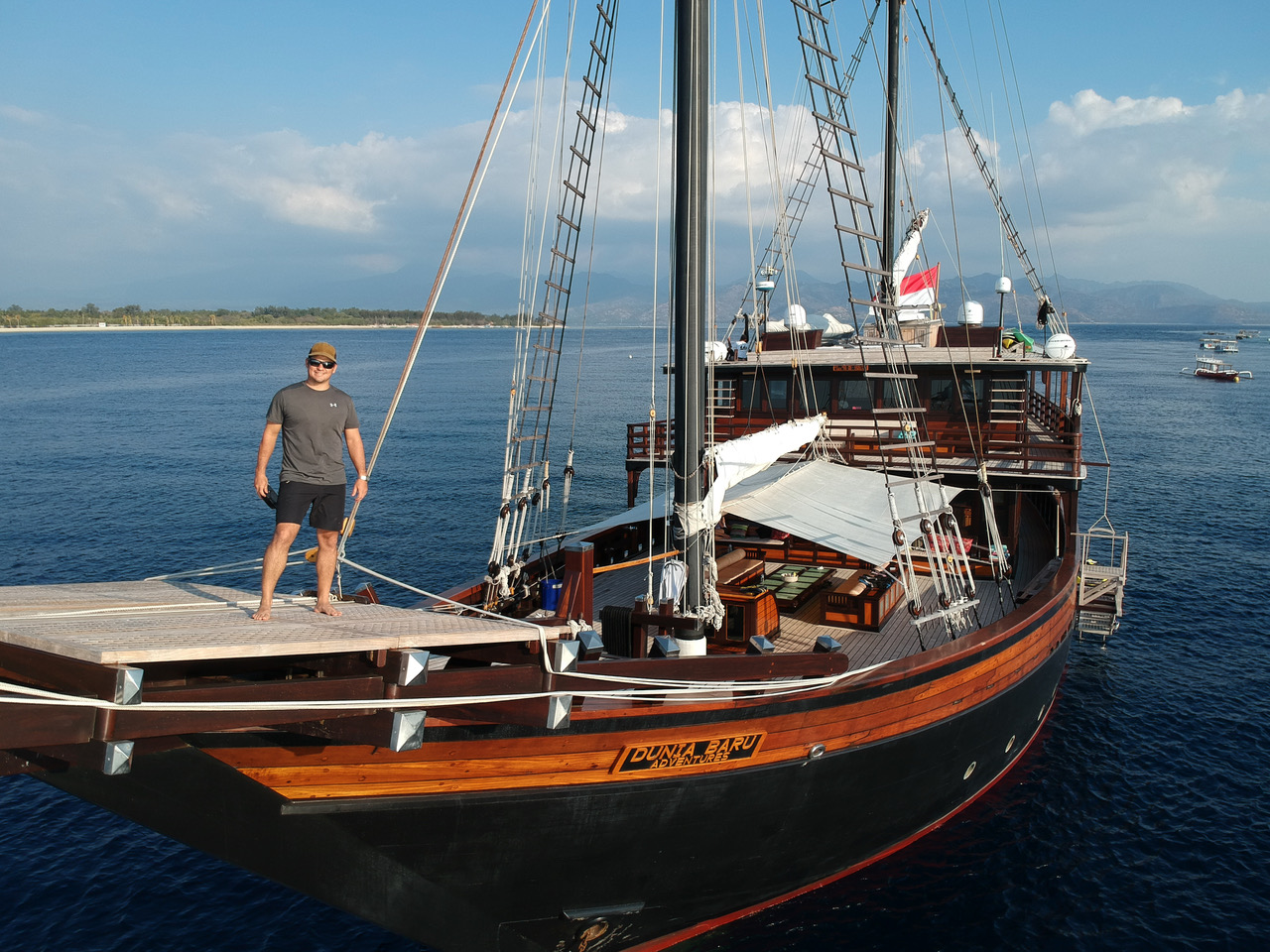 man smiling on bow of luxury wooden yacht Dunia Baru in Indonesia