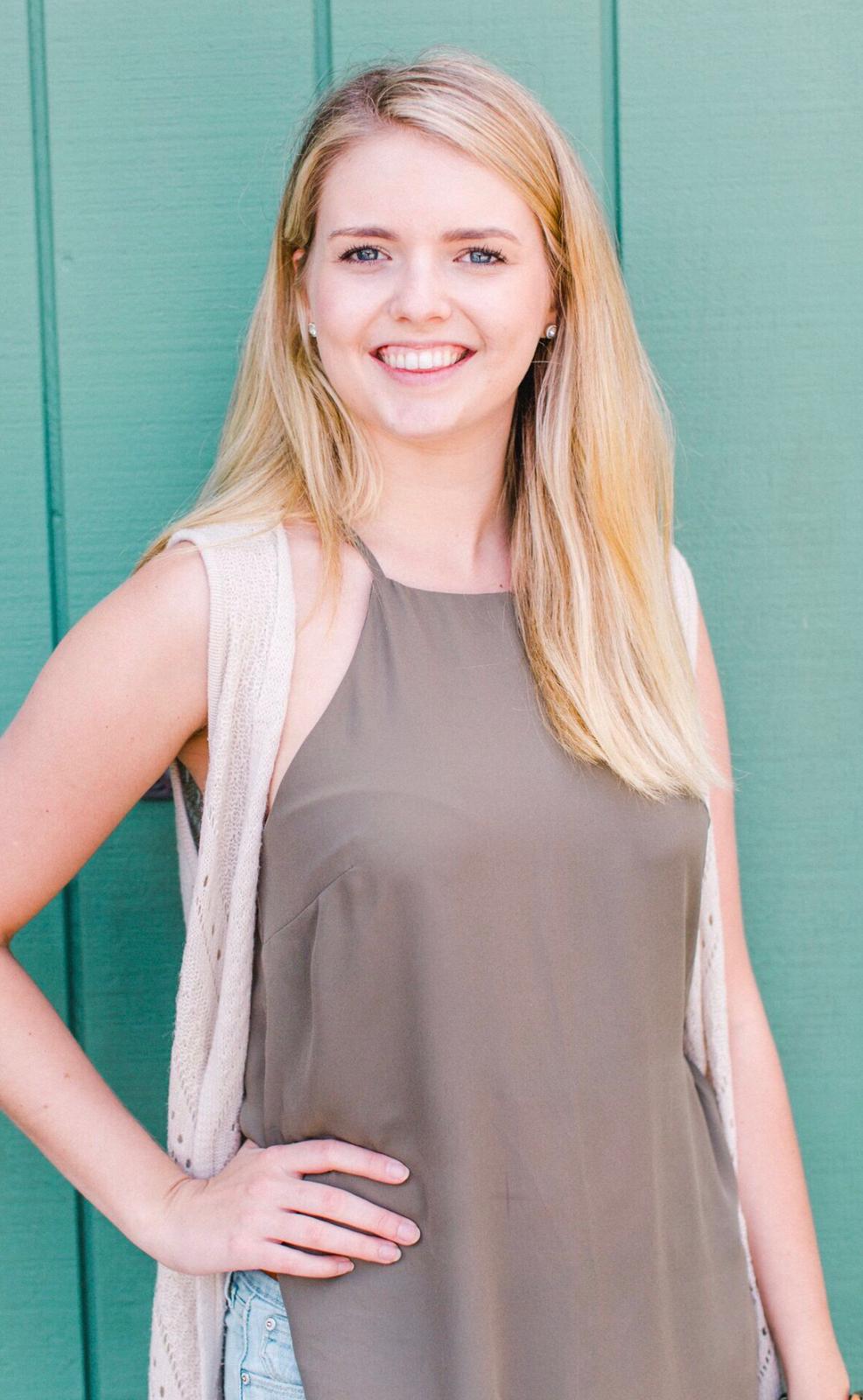 blonde woman smiling in front of teal wall