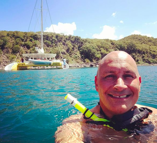 Travel TV host Scott Eddy snorkelling with catamaran in the background