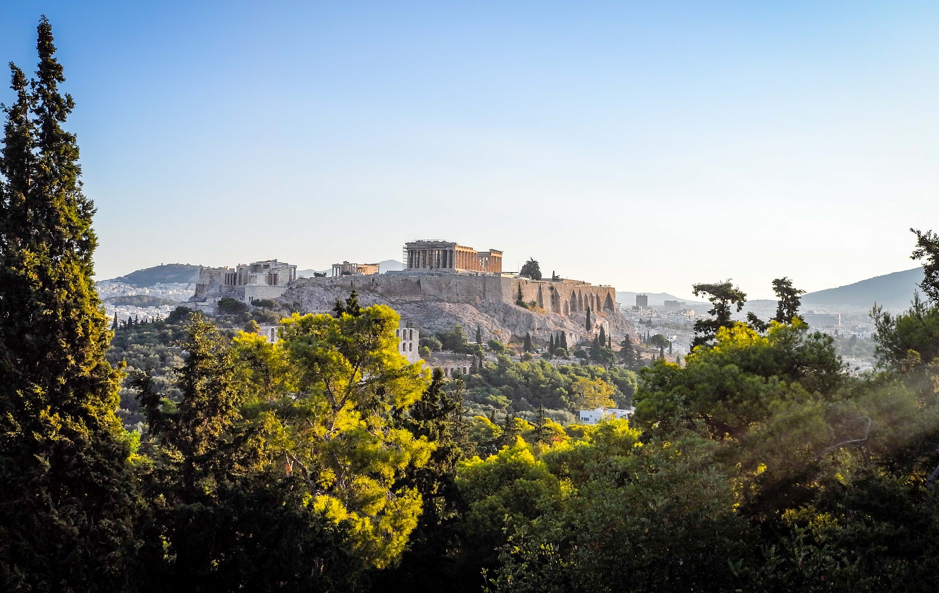 shot of the Acropolis in Athens at a distance with trees in the foreground