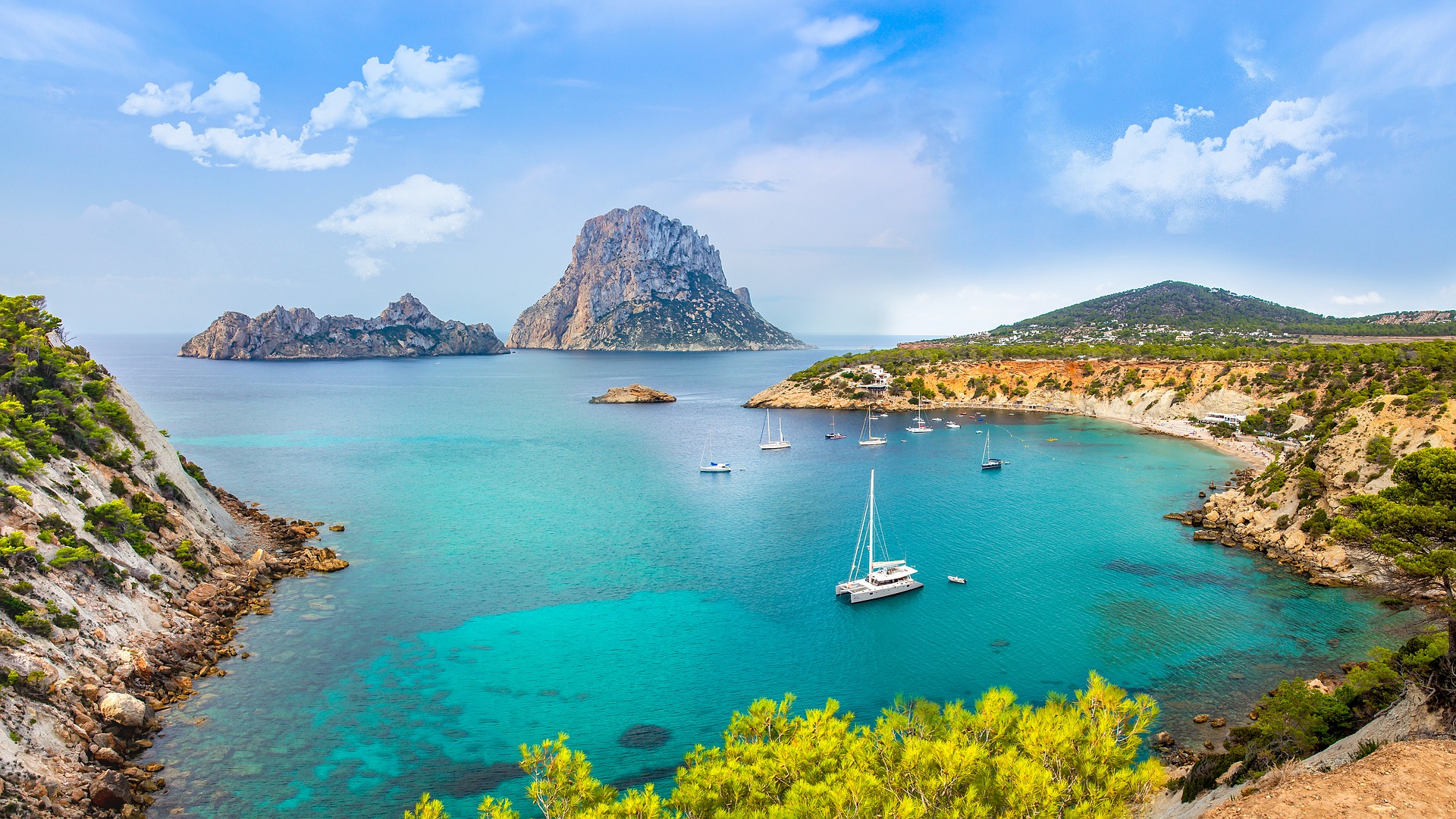 aerial view of beach and boats at anchor in Ibiza with islands in the background