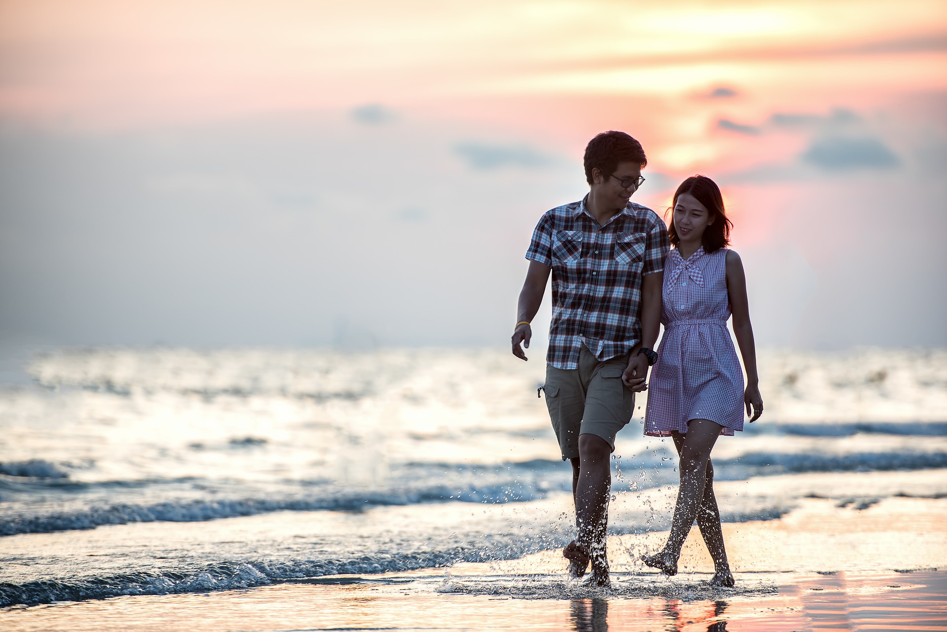 Asian couple walking on the beach at sunset