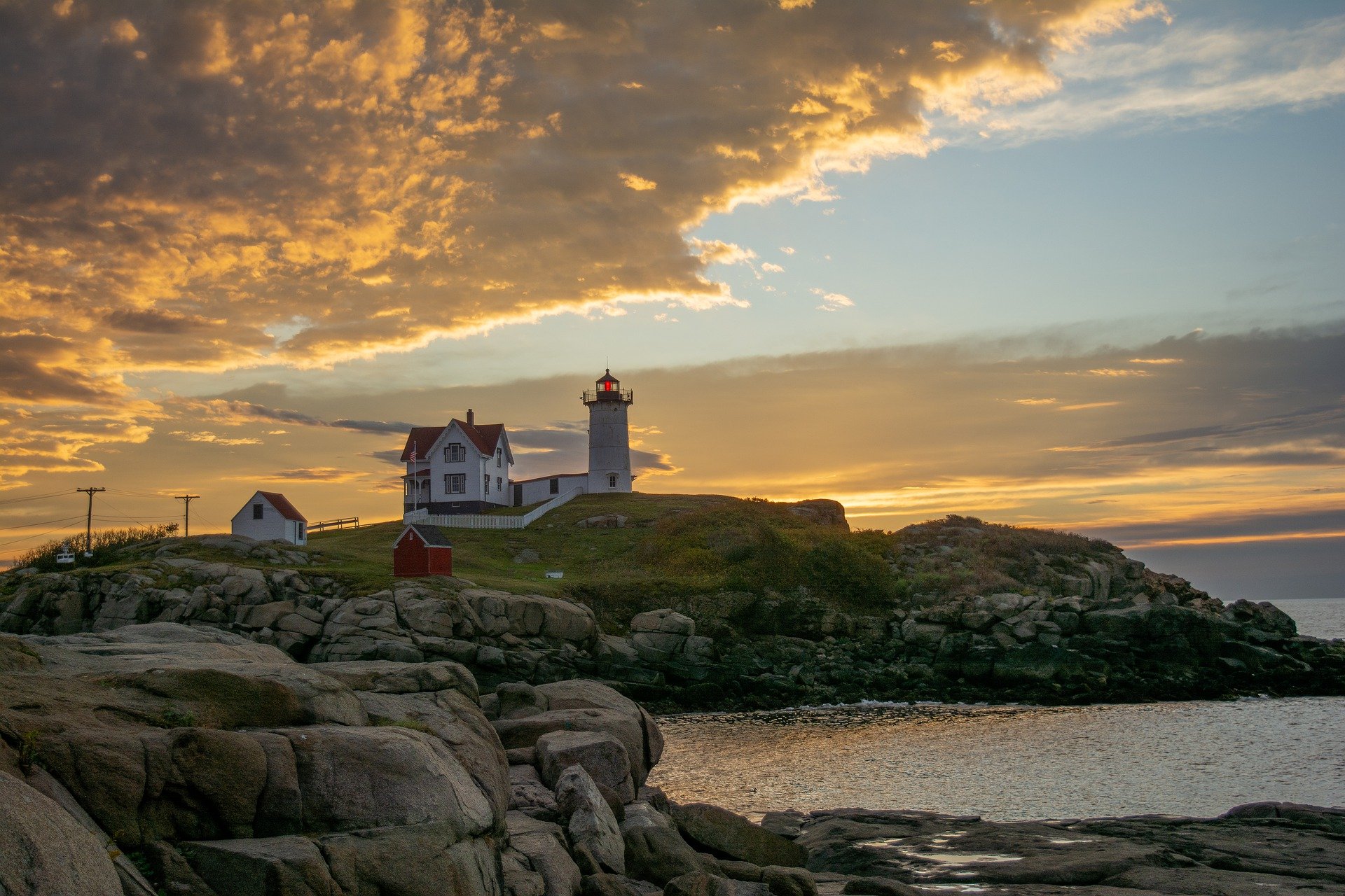 lighthouse at sunset on rocky cliff off coast of New England