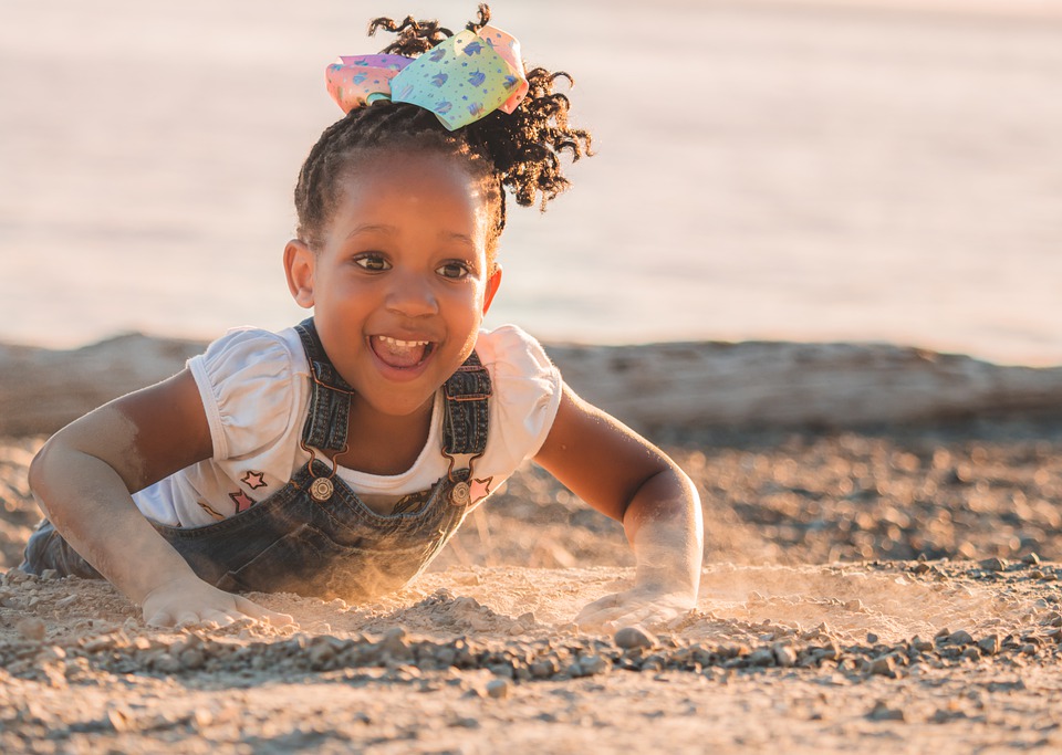 Black child playing on the beach in the sand