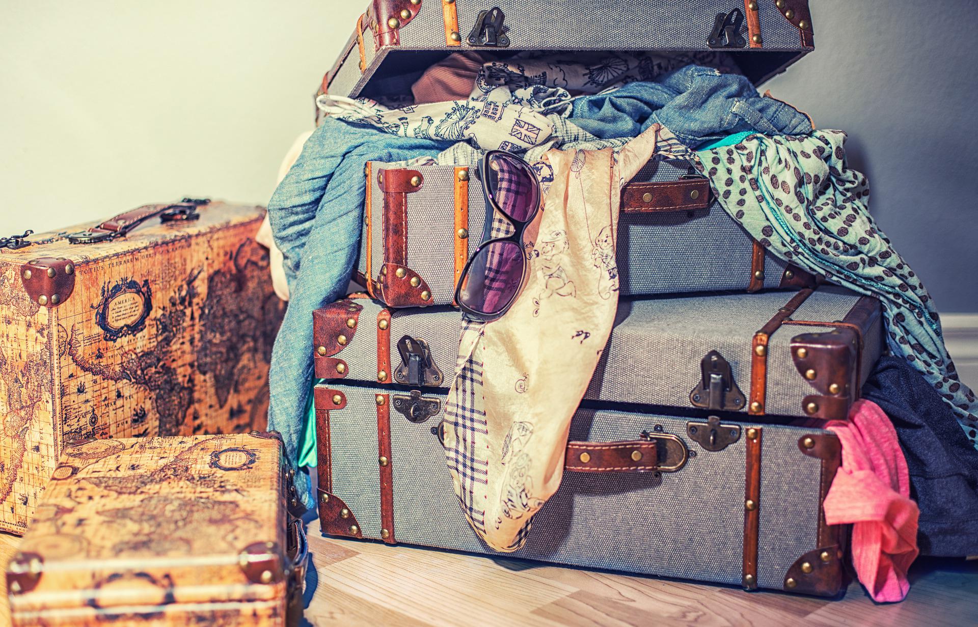 stack of suitcases with clothes tumbling out
