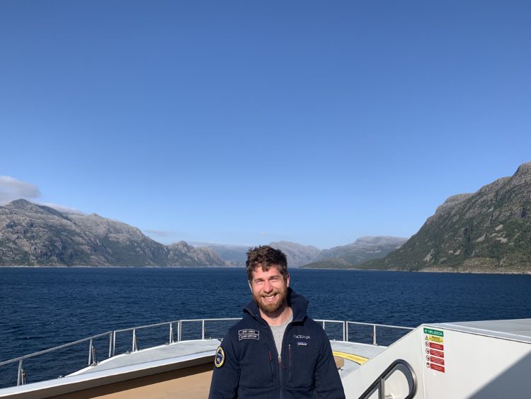 Captain Taigh McManus on the bow of a yacht at sea